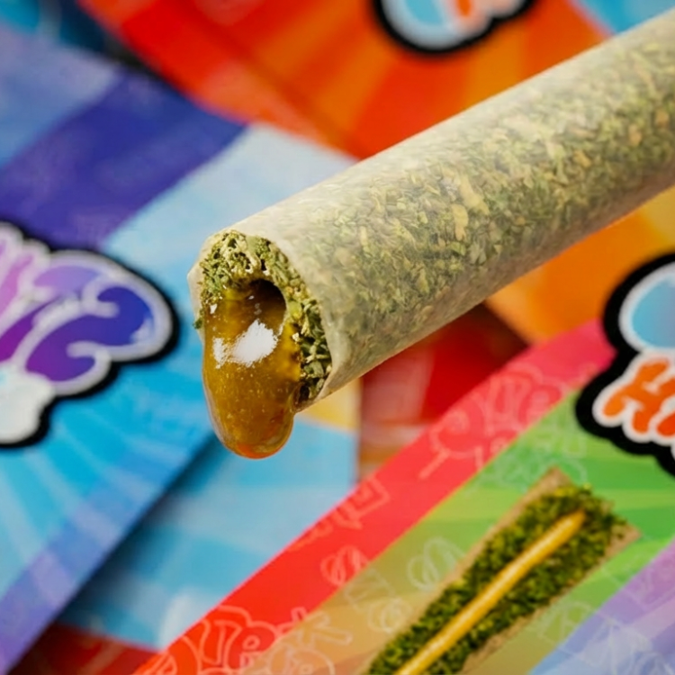 Cannabis joint with colorful packaging in the background